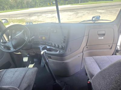 Cab interior of a 2019 Freightliner Cascadia midroof showing steering wheel, dashboard controls, gear shift, and driver seat.