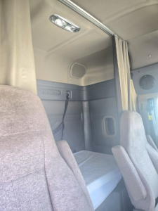 Truck sleeper cab interior with bunk bed and seats in a Freightliner Cascadia, no visible labels or fluid reservoirs readable.