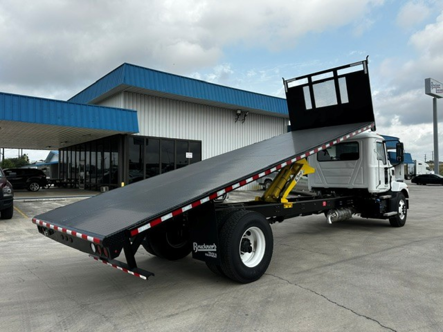 Flatbed tow truck with a raised incline bed on a Mack MD6 chassis; visible text on the rear wheel area reads 'Bruckers' or similar; no other legible labels visible.
