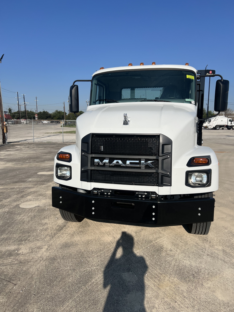 Mack MD6 truck front view showing grille with MACK emblem and bumper, white cab, large mirrors, daytime running lights.