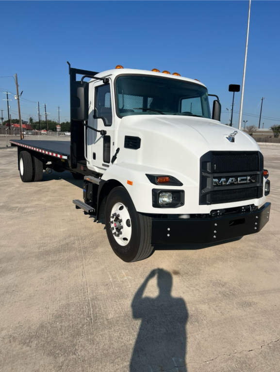 Mack MD6 flatbed truck in white, front and side view with flatbed and dual rear wheels.