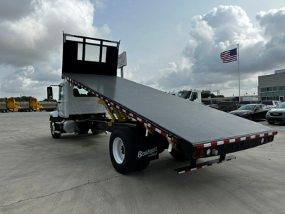 Mack MD6 flatbed truck rear view showing aluminum ramp, hydraulic tilting bed, and dual rear wheels.