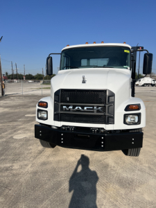 Mack MD6 truck front view showing grille with MACK emblem and bumper, white cab, large mirrors, daytime running lights.