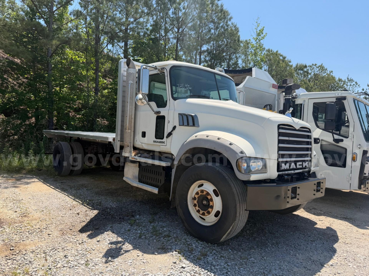 2013 Mack Granite heavy-duty truck with flatbed, front view showing Mack grille and front bumper.