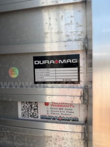 Mack Granite truck body label plate on metal exterior showing DURA-MAG branding and warranty form; close-up view of serial tag and QR-style sticker.