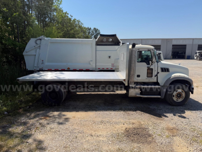 Mack Granite flatbed dump truck side view showing white cab and dump bed with metal flatbed extension, stock number 18899-31 listing.