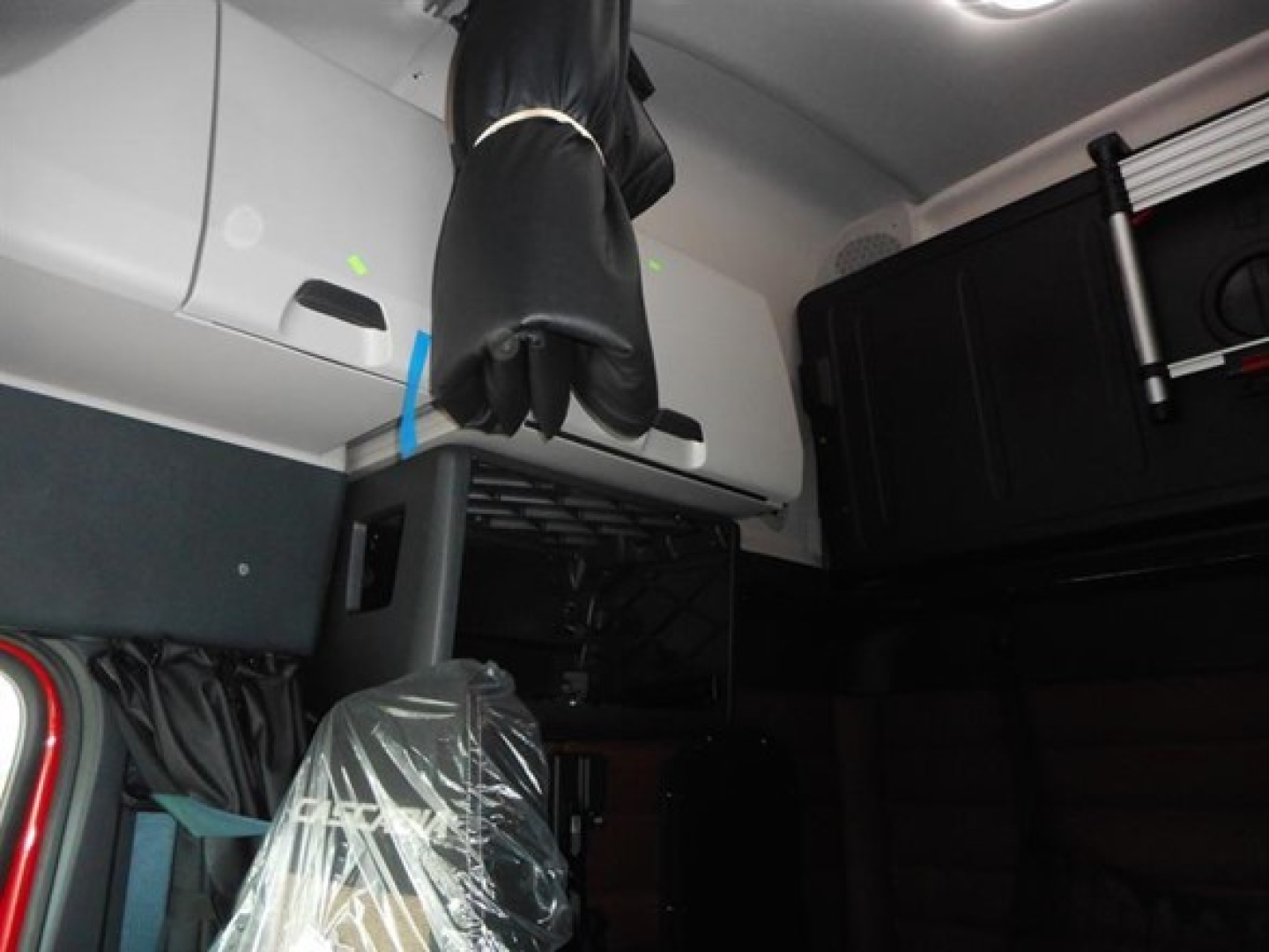 Freightliner Cascadia interior cab area showing overhead storage and bunk space with light gray panels.