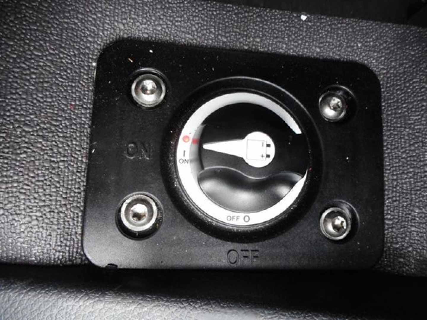 Cab switch panel with circular dial showing On/Off positions, located in a textured black surface inside a Freightliner Cascadia cab.