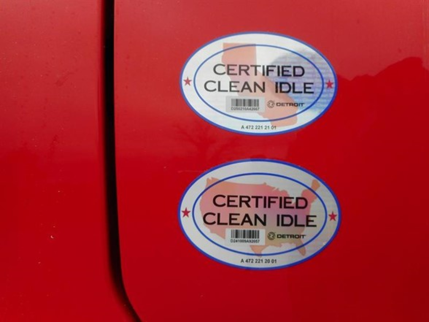 Freightliner Cascadia truck showing two 'Certified Clean Idle' badges on red door.
