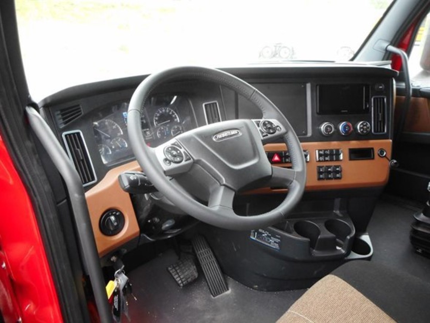 Freightliner Cascadia interior showing steering wheel, dashboard, and center console with controls.