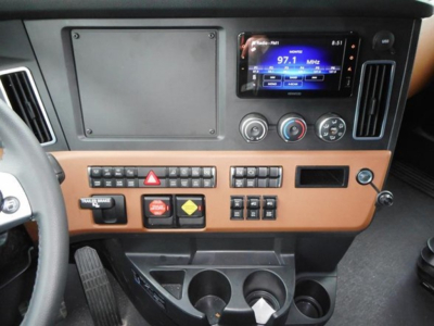 Dashboard and center console of a Freightliner Cascadia 126 showing control panel, touchscreen display, climate controls, and cup holders.