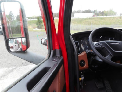 Cab interior of a Freightliner Cascadia_Sleeper showing steering wheel, dashboard, and driver's door with mirror visible.