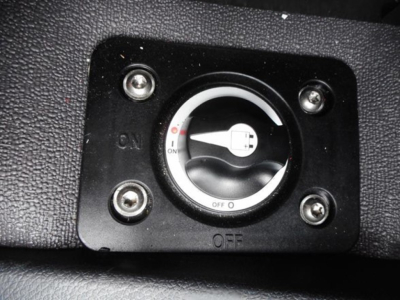 Cab switch panel with circular dial showing On/Off positions, located in a textured black surface inside a Freightliner Cascadia cab.
