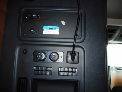 Dashboard area of a Freightliner Cascadia cab showing HVAC controls and a microphone/air switch, with a small sticker and panel details.