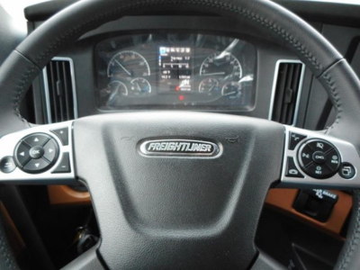 Steering wheel with Freightliner emblem in center, dashboard gauges and control buttons visible.
