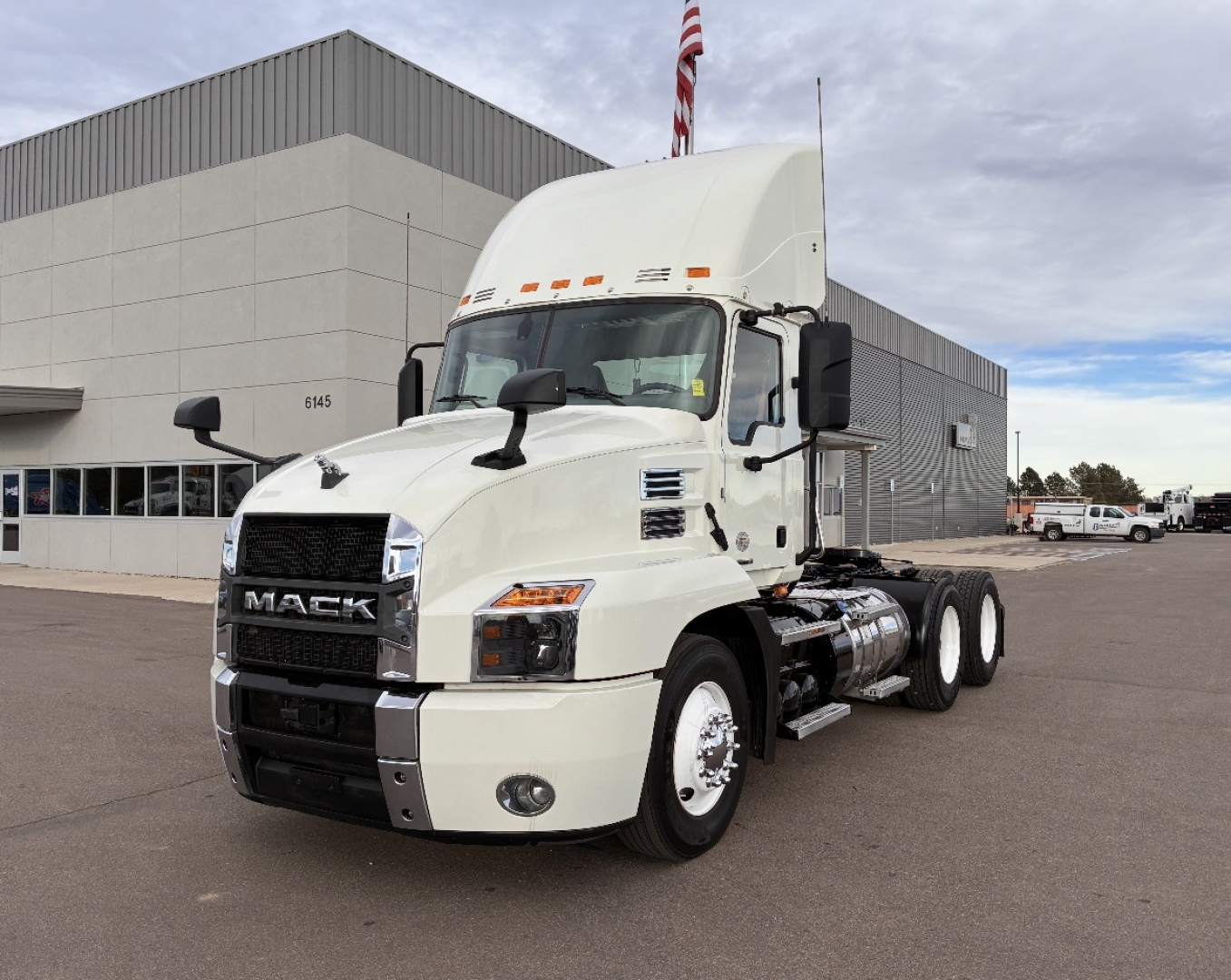Mack AN64T conventional daycab truck in a dealership lot showing front and side profile with white cab and dual rear axles.