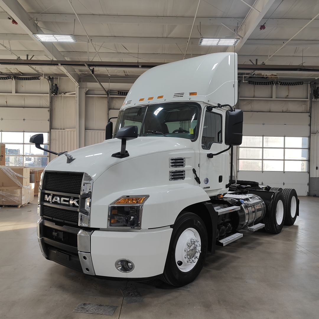 Mack AN64T conventional daycab tractor in white, front three-quarter view showing grille, headlights, mirrors, and fuel tanks.