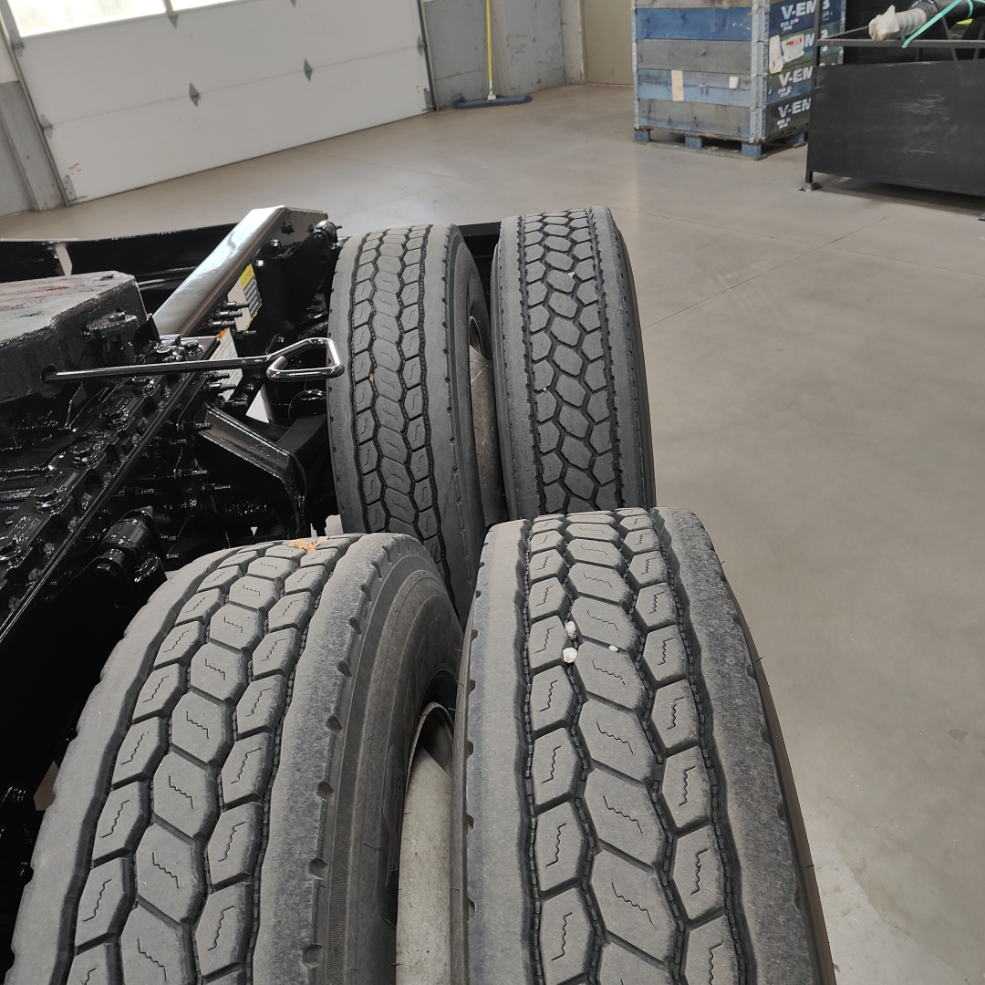 Truck rear dual axle wheels and chassis of a Mack AN64T daycab showing two left rear tires and dual tires, with visible tread pattern.