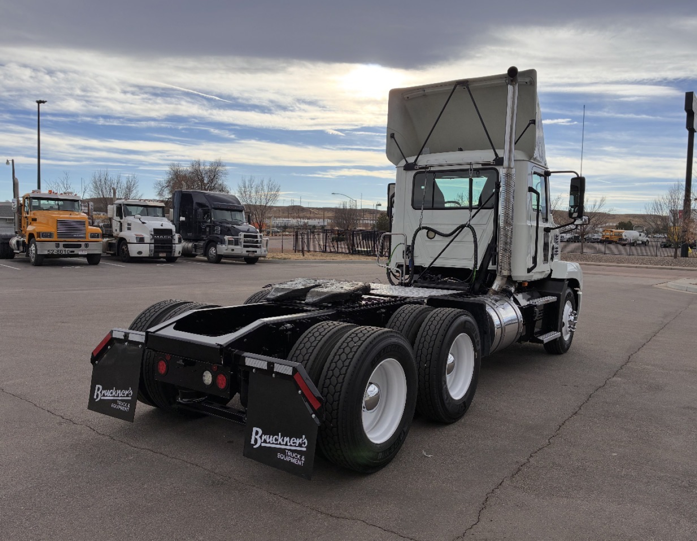 Truck rear view showing fifth wheel and dual rear axles of a white 2020 Mack AN64T conventional daycab with Brunker’s mud flaps.