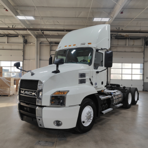 Mack AN64T conventional daycab tractor in white, front three-quarter view showing grille, headlights, mirrors, and fuel tanks.