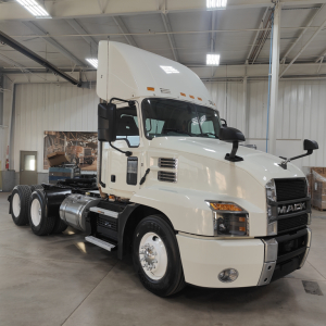 Mack AN64T conventional daycab tractor in showroom, 2020 model year, white cab with large grille and exhaust stacks.
