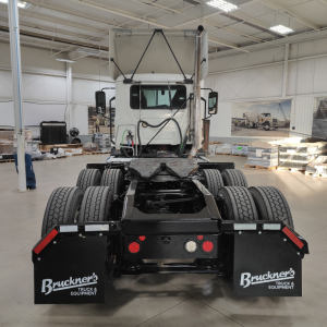 Rear view of 2020 Mack AN64T daycab, dual rear axles, fifth-wheel area, show in-service truck with Bruckner's mud flaps and triple-axle configuration.
