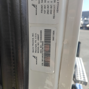 Mack truck identification label showing VIN and stock information on door frame: 'MACK TRUCKS INC.', 'MODEL NO. G', barcode, and numbers. Visible text includes VIN, stock number B2719P, and label with manufacturing info.
