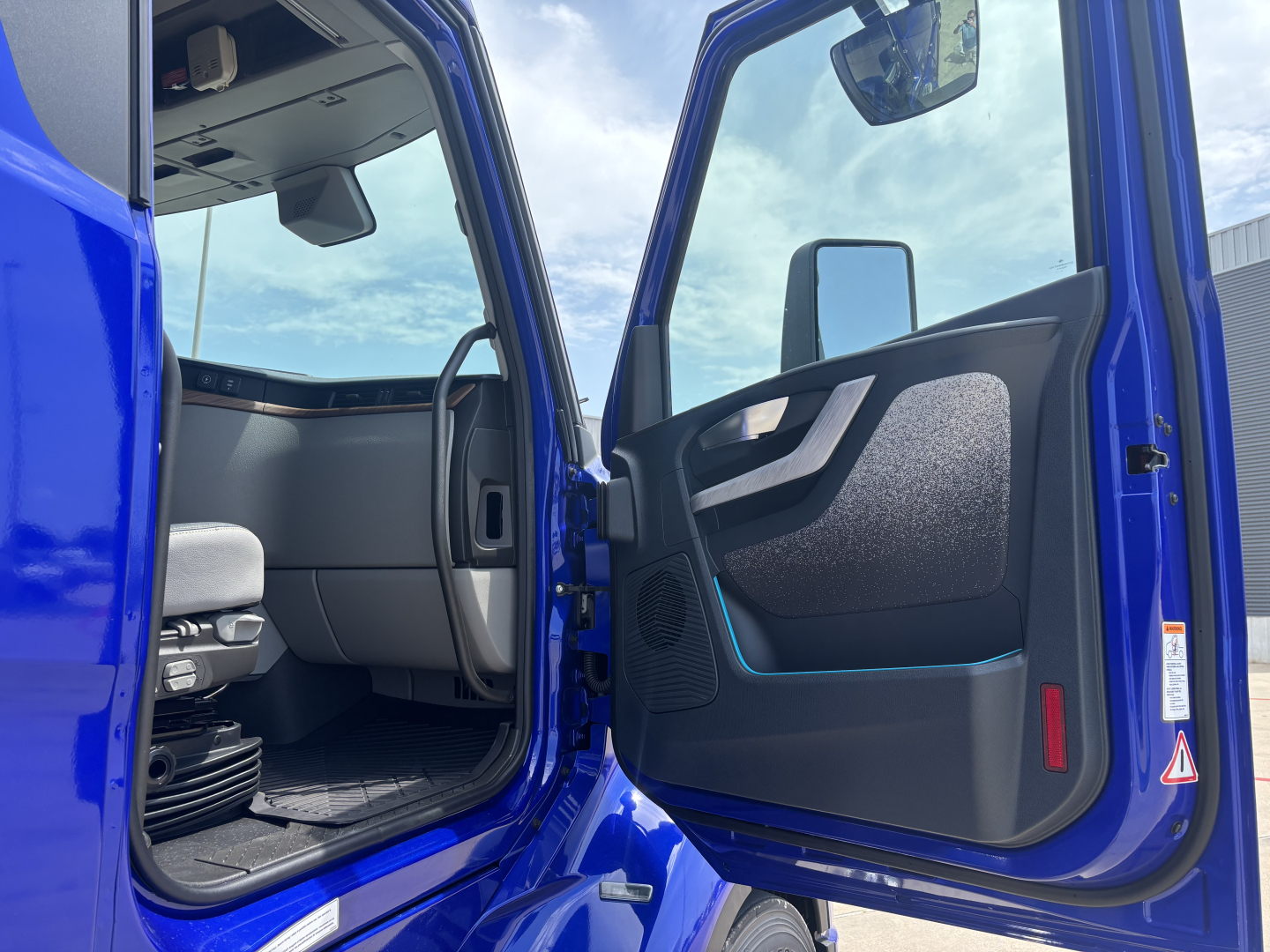Blue Volvo VNL64T860 truck cab interior with open door showing driver seat and doorway.