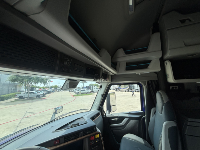 Interior view of a Volvo VNL64T860 truck cabin showing dashboard, overhead storage, and sleeper area.
