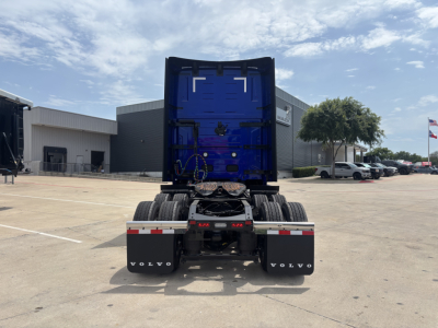Volvo VNL64T860 tractor rear view showing blue sleeper cab, dual rear axles, and black Volvo mudflaps with white Volvo logos.