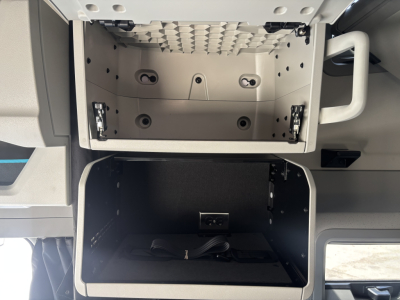 Volvo VNL64T860 truck cab storage compartments with empty upper tool box and lower storage bay, visible wiring, and side handle.