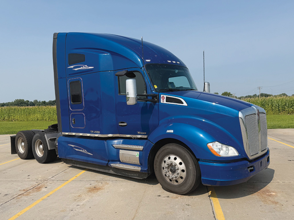 Kenworth T680 tractor in blue, side view showing front grille, cab with chrome mirrors, step boards, fuel tanks, and dual rear axles.