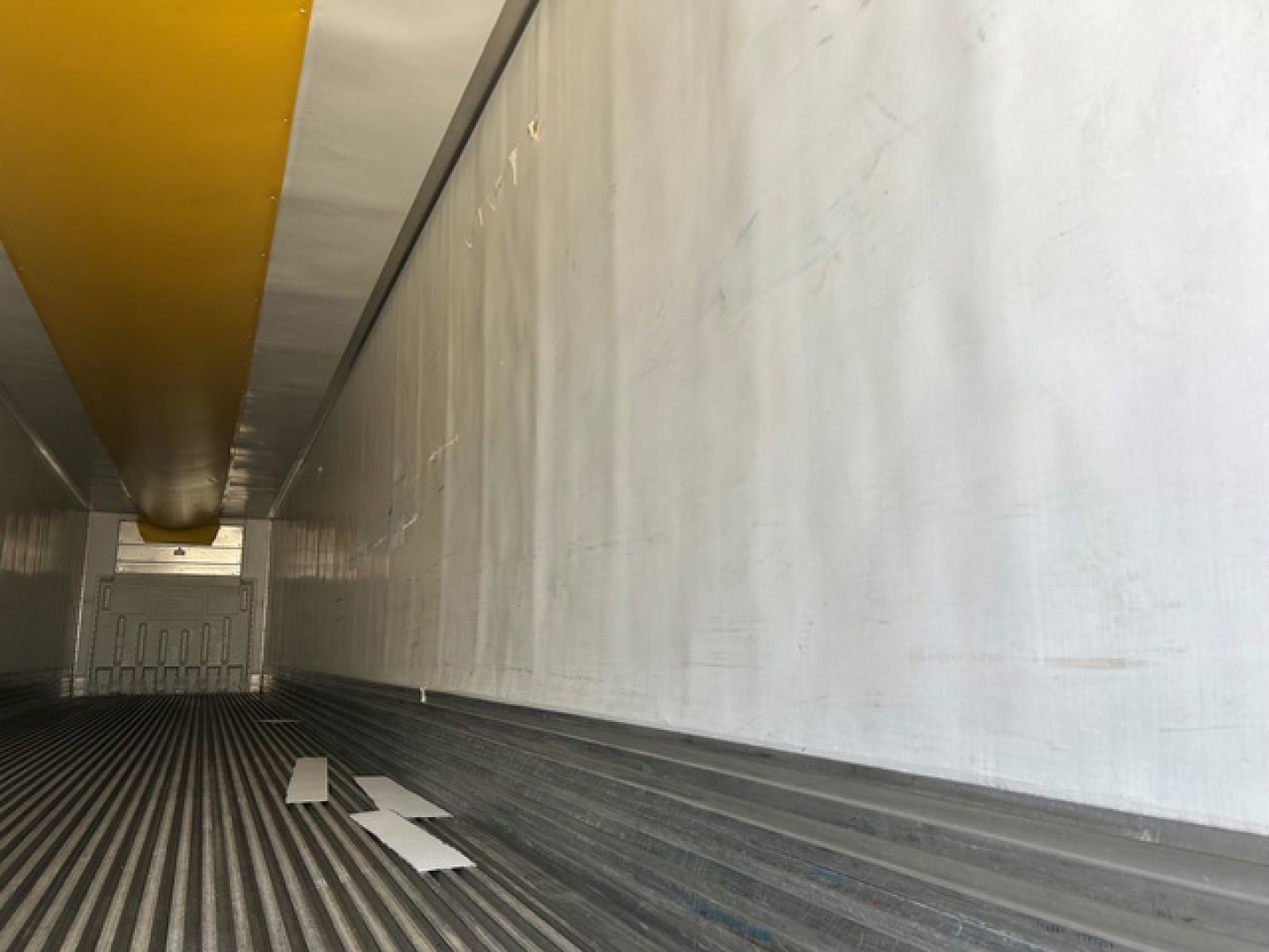 Inside view of a 2020 Utility reefer trailer cargo area with ribbed floor, white walls, and yellow ceiling beam.
