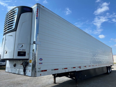 Refrigerated trailer with Thermo King unit at the front showing multiple side panels and wheels, utility reefer trailer in a lot.
