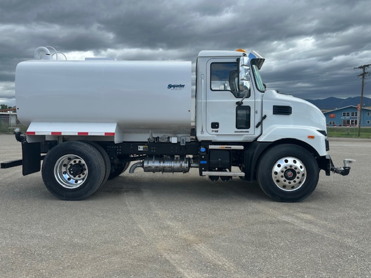 Water truck chassis side view showing 2025 Mack MD7 with large cylindrical tank and frontend cab.