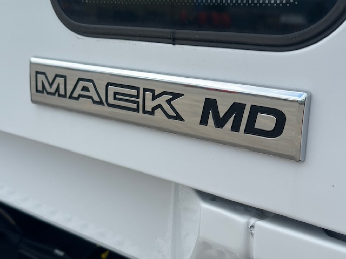 Mack MD badge on white truck exterior showing MA CK MD chrome emblem.
