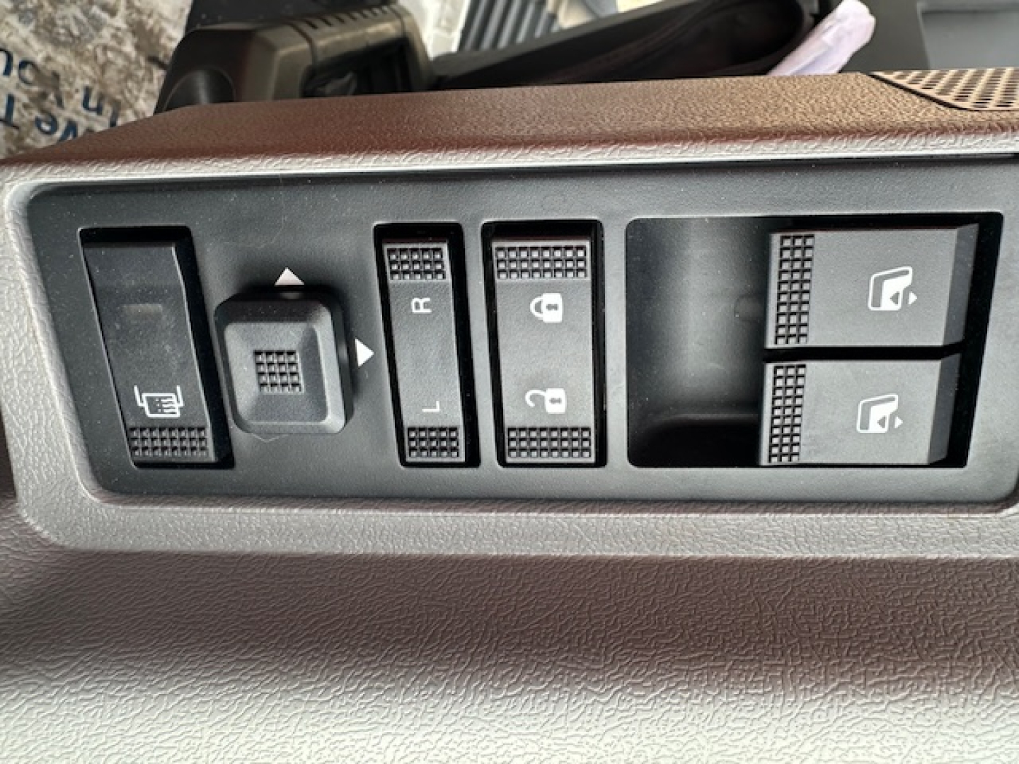 Dashboard switch panel showing window/locking controls and mirror adjusters. Visible text includes L, R on mirror switch, lock/unlock icons, and window buttons.