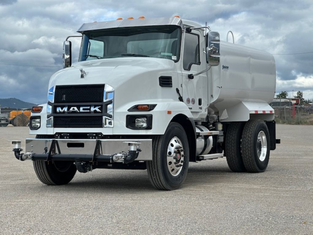 Mack MD7 tilt-cab truck with white body and tanker, front grille displays MACK, dual headlights, chrome bumper, and orange clearance lights on cab roof.