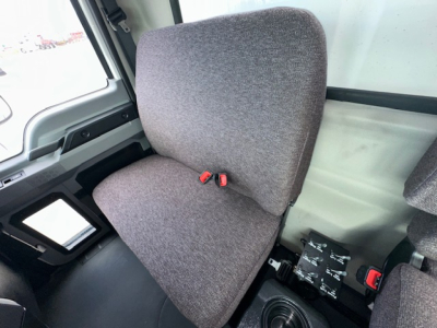 Cab interior of a 2025 Mack MD7 showing seat upholstery and a small control panel with switches and a red latch.