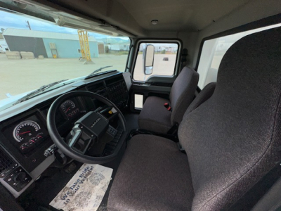 Cab interior of a 2025 Mack MD7 truck showing steering wheel, dashboard, driver and passenger seats, and side window.