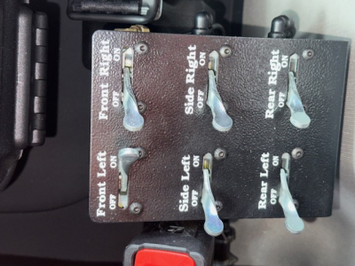 Control panel with six toggle switches labeled Front Right, Side Right, Rear Right, Front Left, Side Left, Rear Left in a truck cab area.