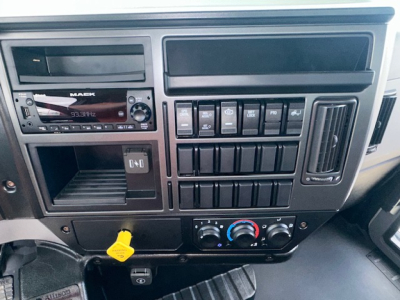 Dashboard of a Mack MD7 truck showing radio, switches, climate controls, and yellow dipstick handle visible in lower area.