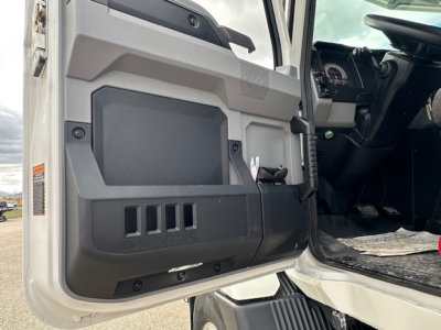 Truck cab interior door panel and open driver door showing dashboard and pedals in a 2025 Mack MD7.