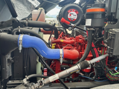 Mack MD7 engine bay showing blue radiator hose, red engine components, and various hoses and wiring.