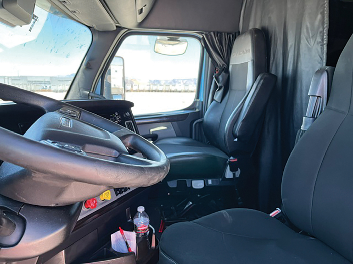 Freightliner Cascadia126 truck interior showing driver's seat and dashboard with steering wheel, gear shifter, and upholstery details.