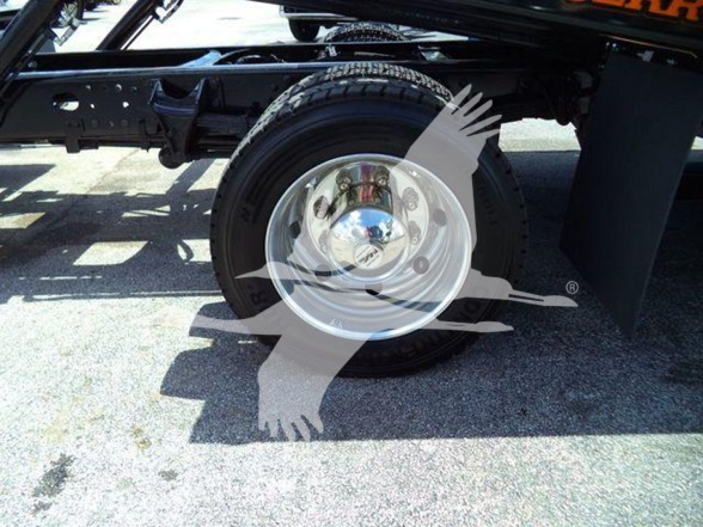 Wheel and suspension area of a 2023 Chevrolet Silverado 6500HD rollback truck showing single rear wheel, chrome hubcap, and chassis components.