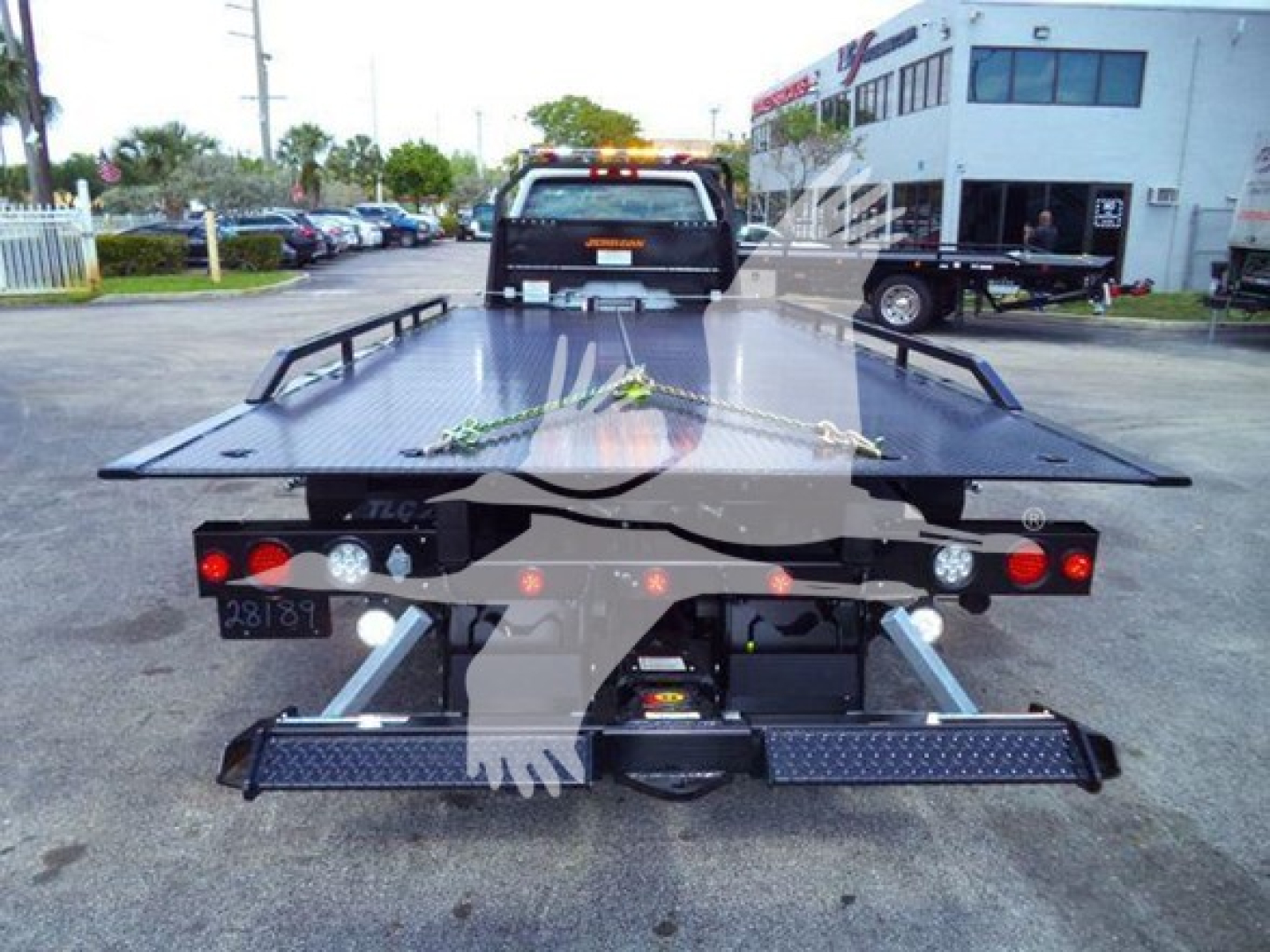 Truck bed and rear view of a rollback tow truck with a flatbed platform and hydraulic winch.