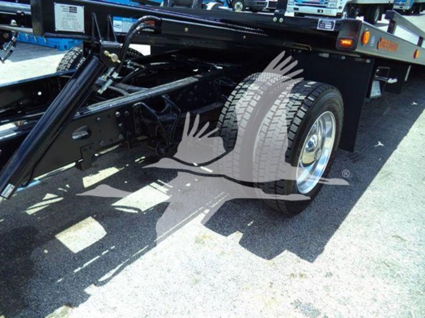 Truck rear/side view showing dual rear wheels, Silverado rollback equipment frame, and hydraulic components.
