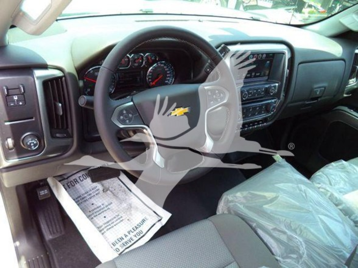 Console and steering wheel view of a Chevrolet Silverado 6500HD interior with touchscreen infotainment and plastic seat covers.