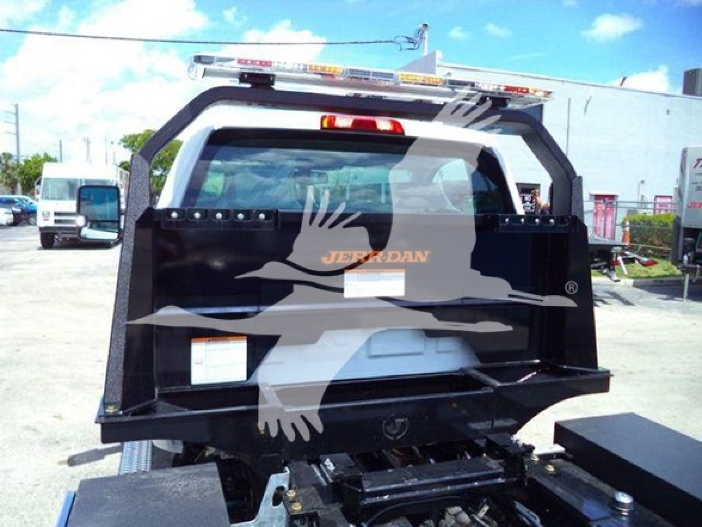 Truck bed showing Jerr-Dan rollover equipment and rear cab window with partial sticker visible.